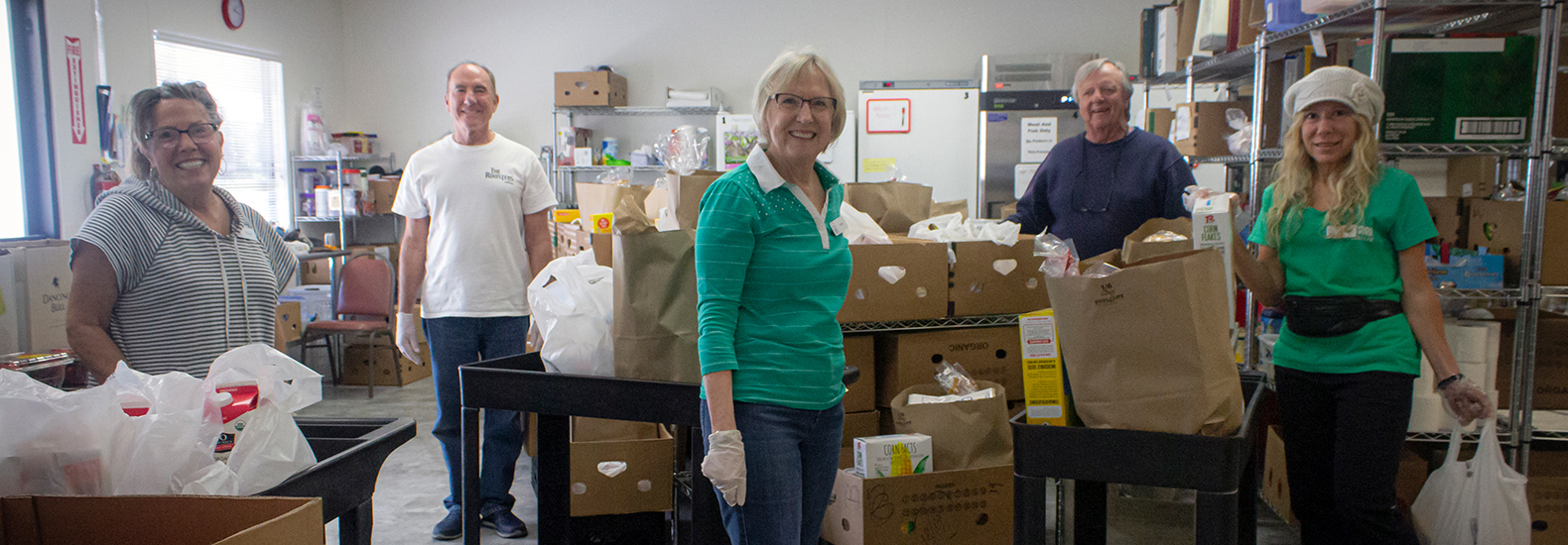 People are volunteering in a food bank, sorting and packing supplies. Food bank partnerships are relevant here.